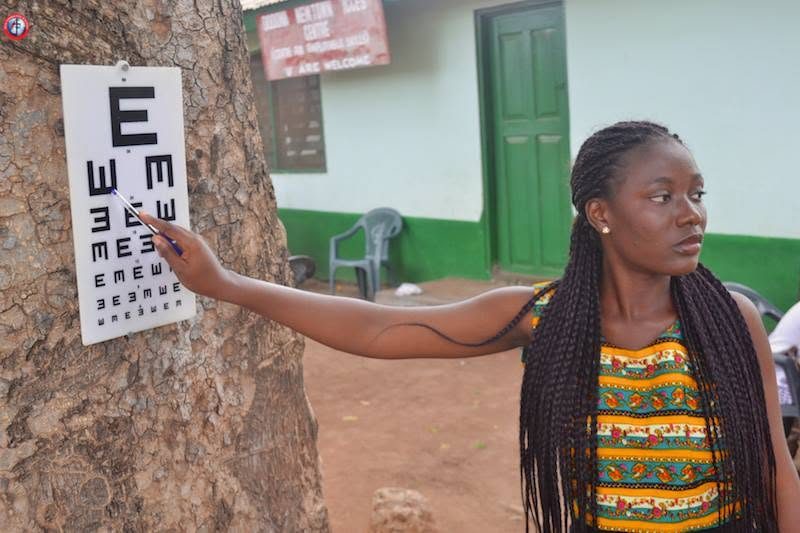 A young woman covering one eye during a sight test at a campaign clinic