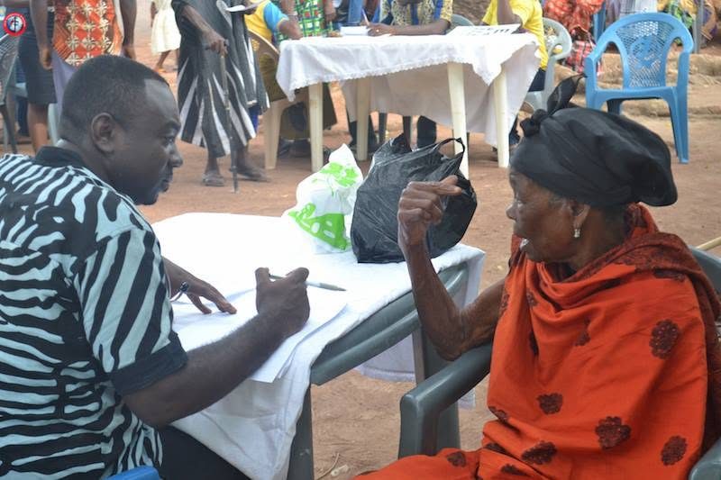 A clinician taking notes with an elderly woman at the campaign